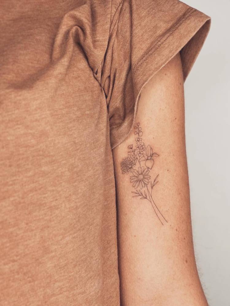 Flower bouquet in fine line style tattooed on the bicep.