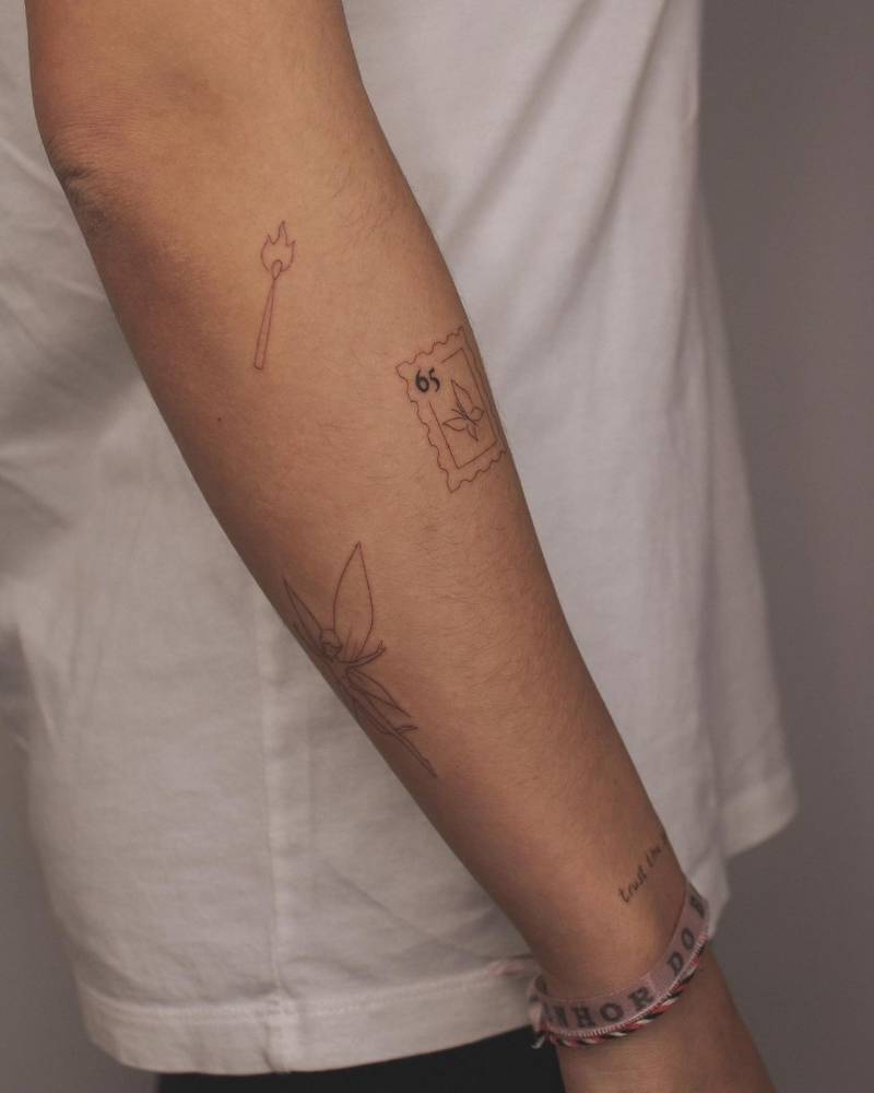 Fine line style fairy, stamp and matchstick tattoos located on the forearm.