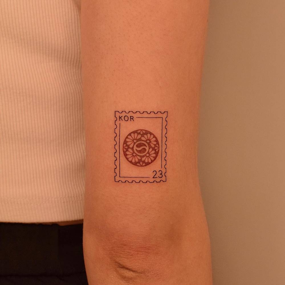 Korean stamp tattooed on the tricep, illustrative style.