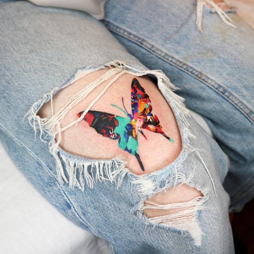Pop art style butterfly tattoo located on the thigh.