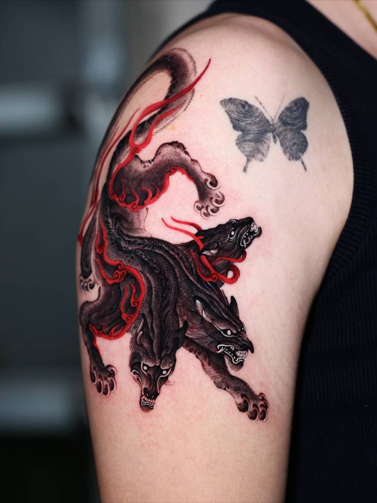 Cerberus tattoo in oriental style located on the upper arm.