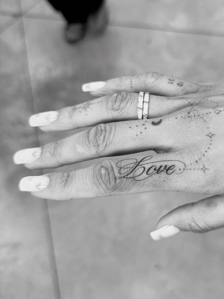 Script font word "love" tattoo located on the finger.