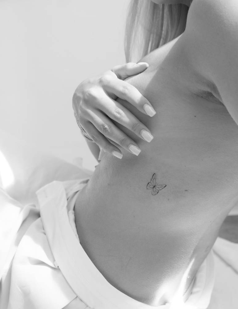 Little fine line butterfly tattoo located on the rib.