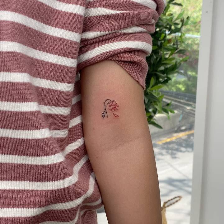 Minimalistic style red rose tattoo located on the bicep.