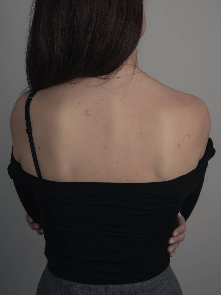 Stars and crescent moon tattoos located on the upper back.