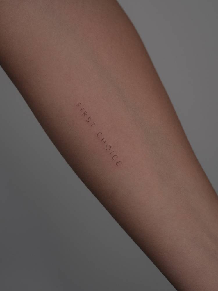 "First choice" lettering tattoo placed on the inner forearm.