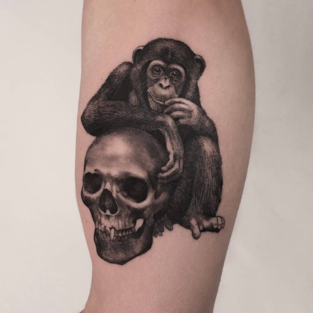 Black and grey style chimp and skull tattoo located on the inner arm.