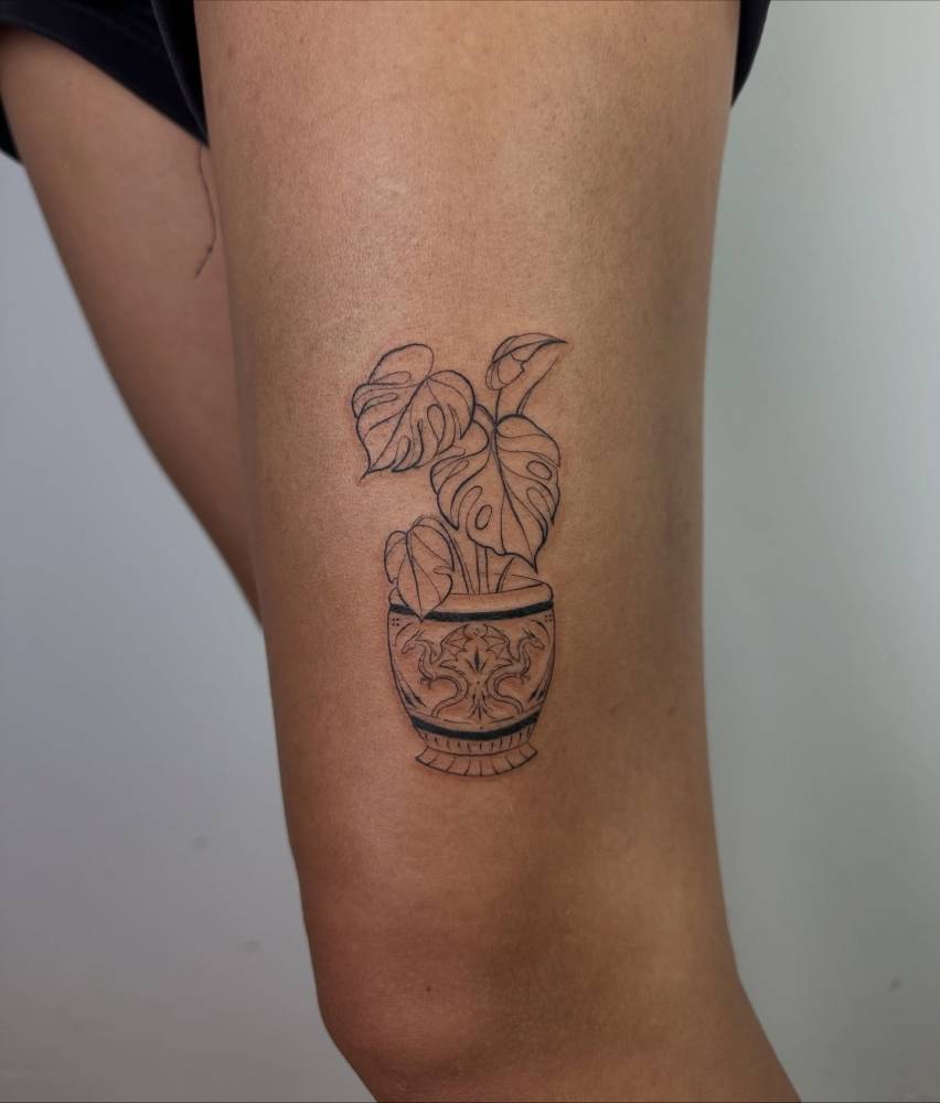 Illustrative style monstera and vase tattoo located on the thigh.