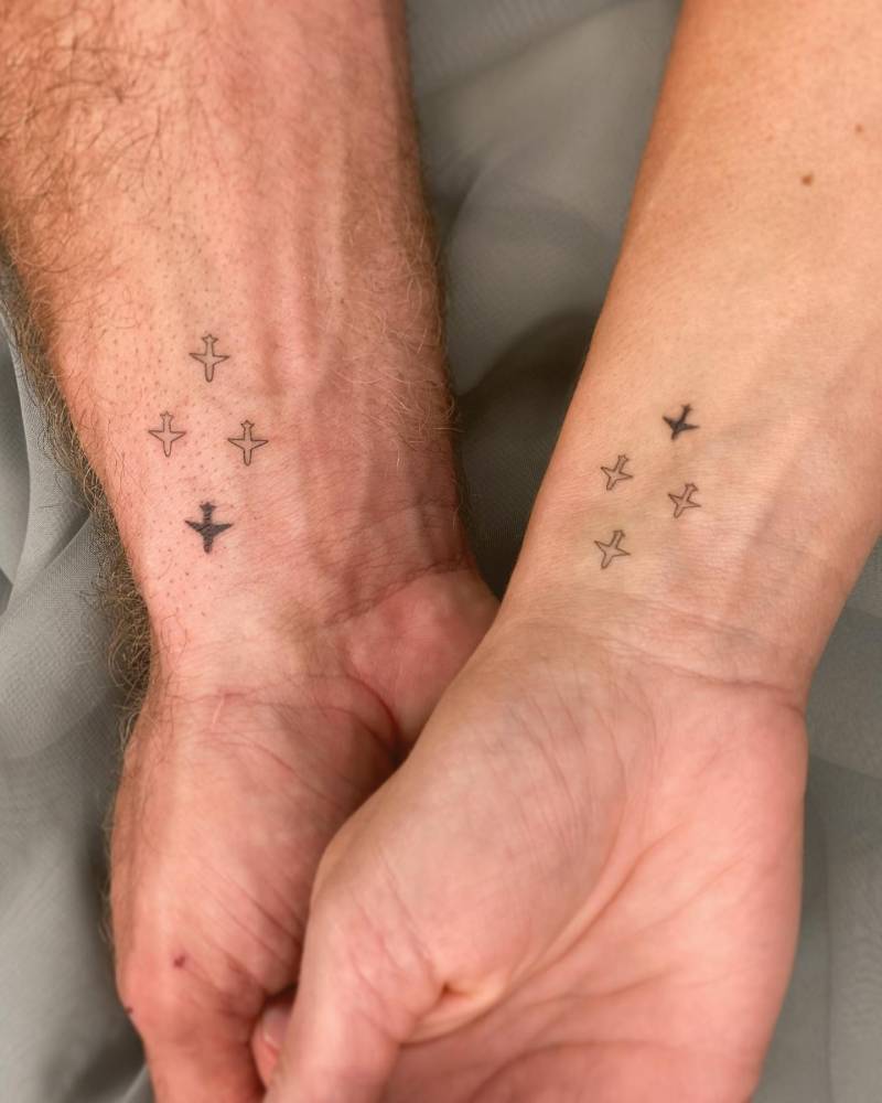Matching airplanes tattoo for couple, minimalistic style.
