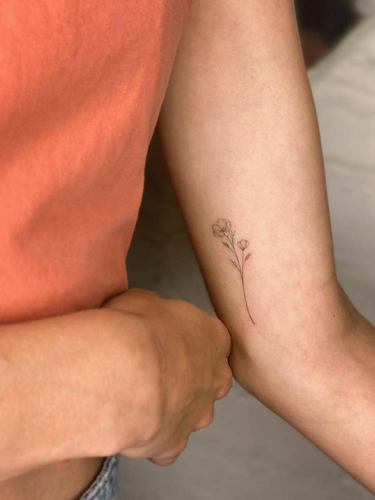 Fine line style flowers tattoo located on the inner arm.