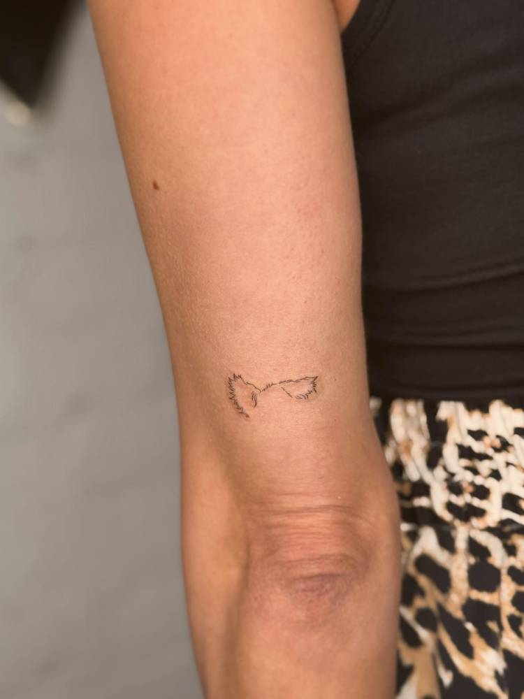 Minimalistic style dog ears tattoo located on the tricep.