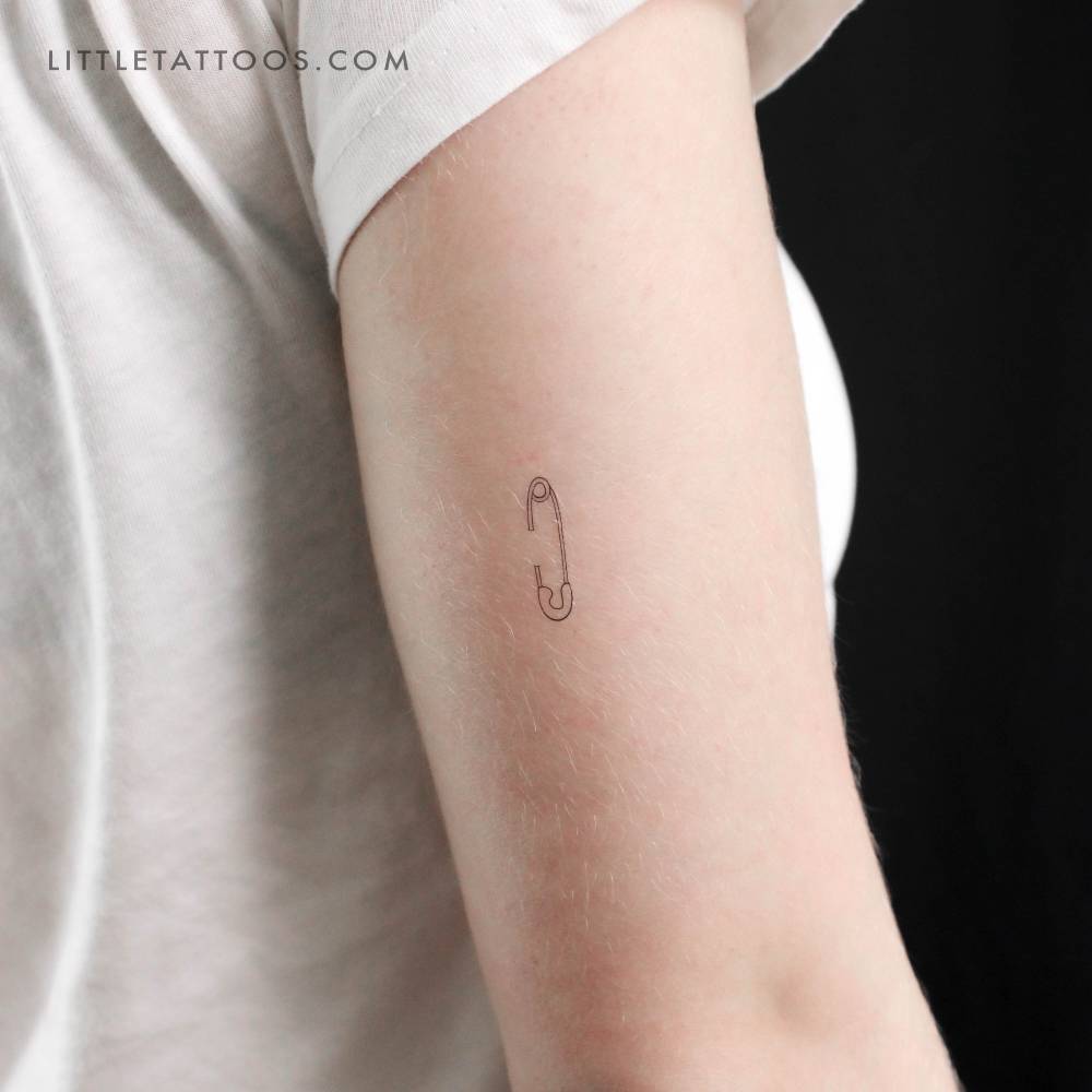 Safety pin temporary tattoo in fine line style located on the tricep.