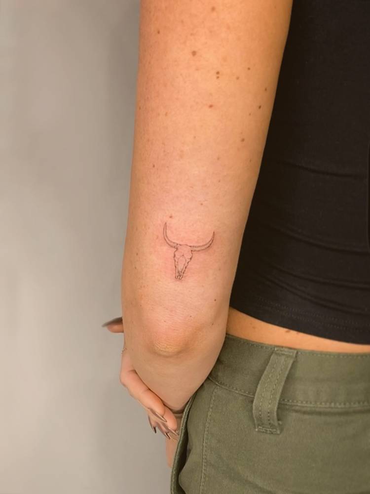 Bull skull tattoo located on the tricep, done in fine line style.