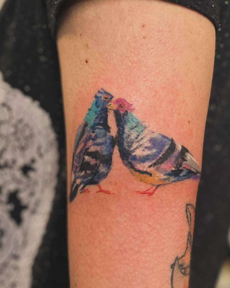 Pigeon couple tattoo located on the upper arm, watercolor style.