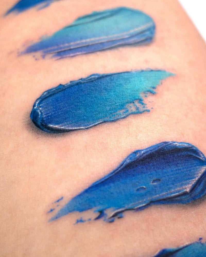 Realistic style brush strokes tattoo located on the thigh.