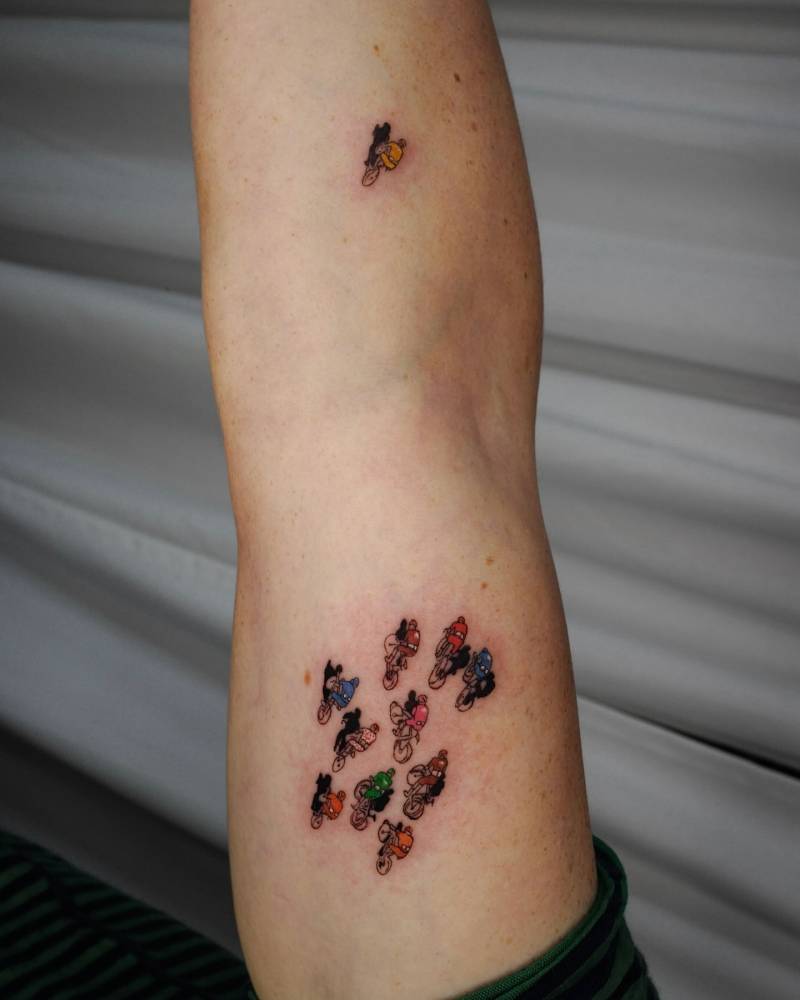 Little cyclists in illustrative style tattooed on the arm.
