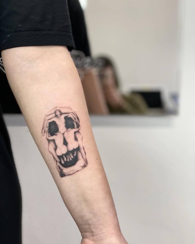 'In Voluptas Mors' tattoo placed on the inner forearm, micro-realistic style.