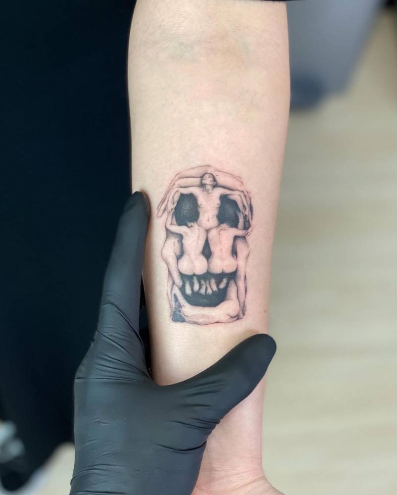 'In Voluptas Mors' tattoo placed on the inner forearm, micro-realistic style.