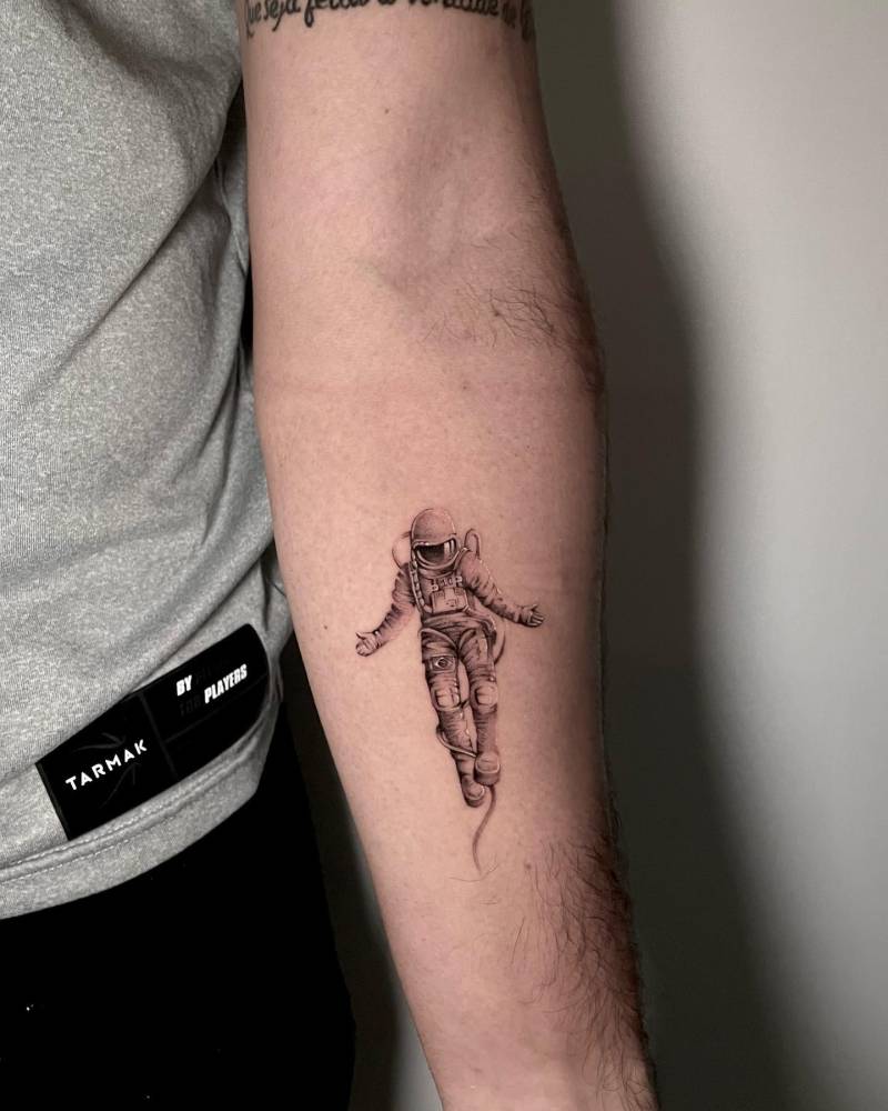 Micro-realistic style astronaut tattoo located on the inner forearm.