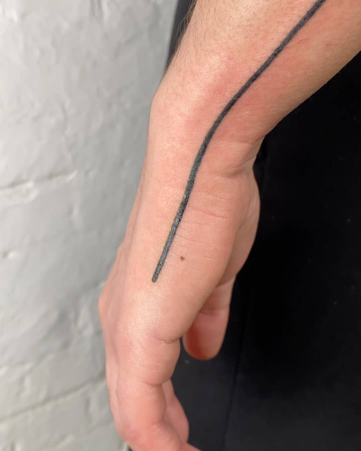 Line tattoo located on the wrist and hand, geometric style.