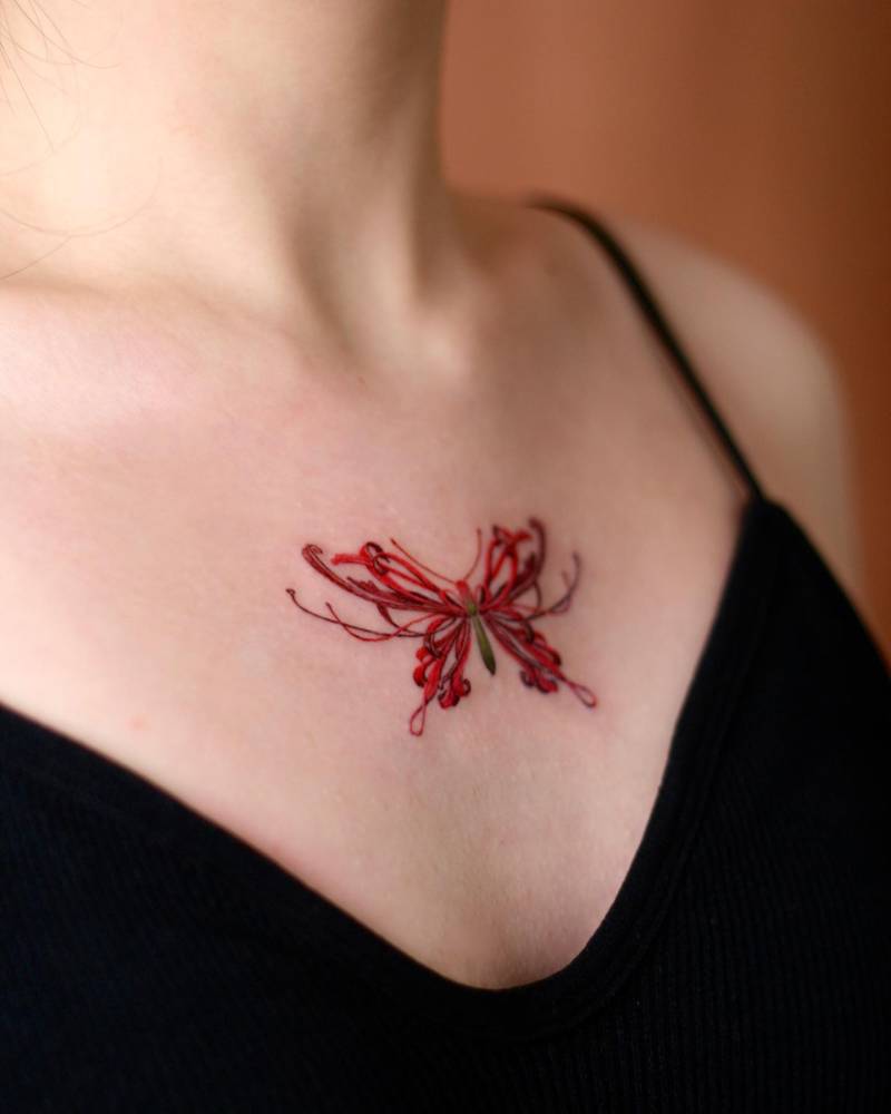 Red spider lily butterfly tattooed on the on the chest.