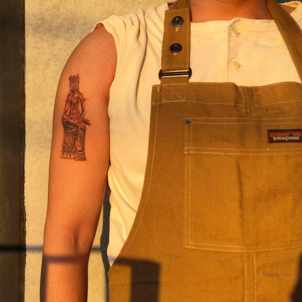 Buddha tattoo located on the upper arm, watercolor style (healed).