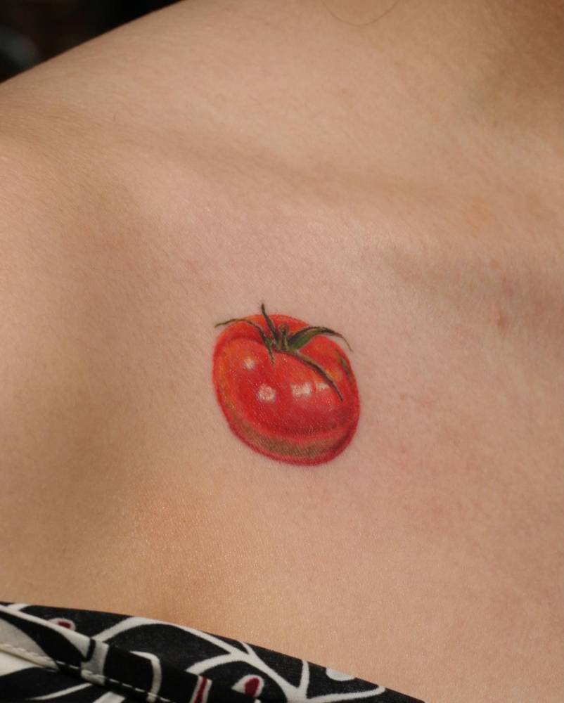 Watercolor style tomato tattoo located on the collarbone.