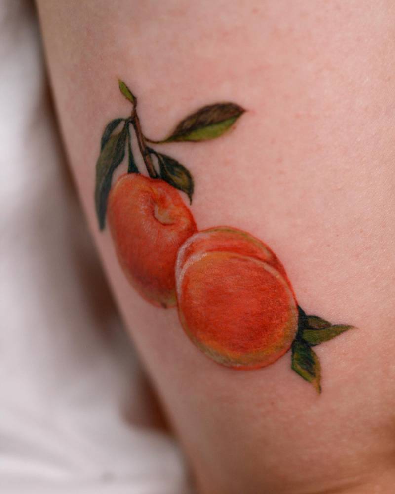 Peaches tattoo in watercolor style located on the tricep.