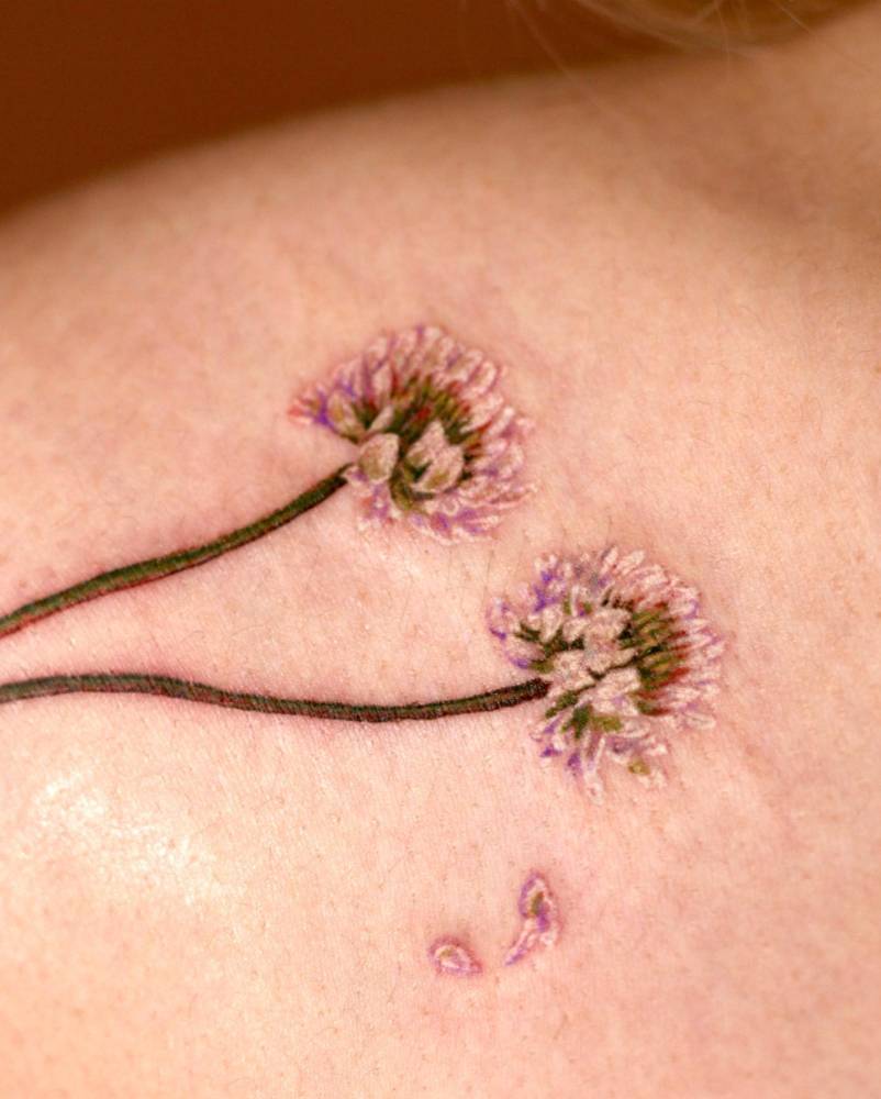 Watercolor style pink clover flower tattoo located on the shoulder.