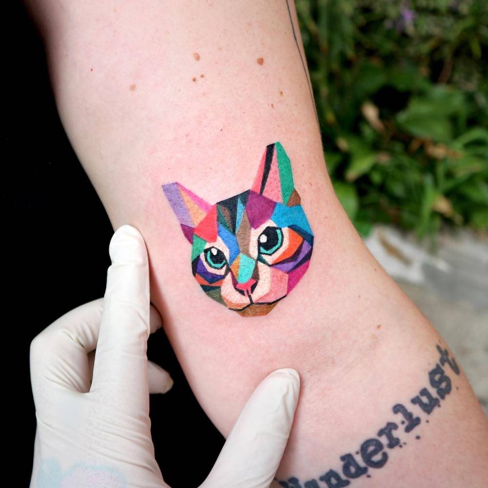 Low poly cat portrait tattoo located on the bicep.