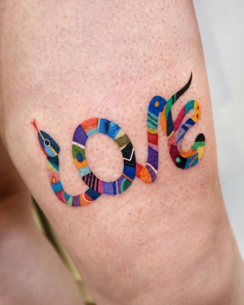 Snake forming the word "love" tattooed on the thigh.