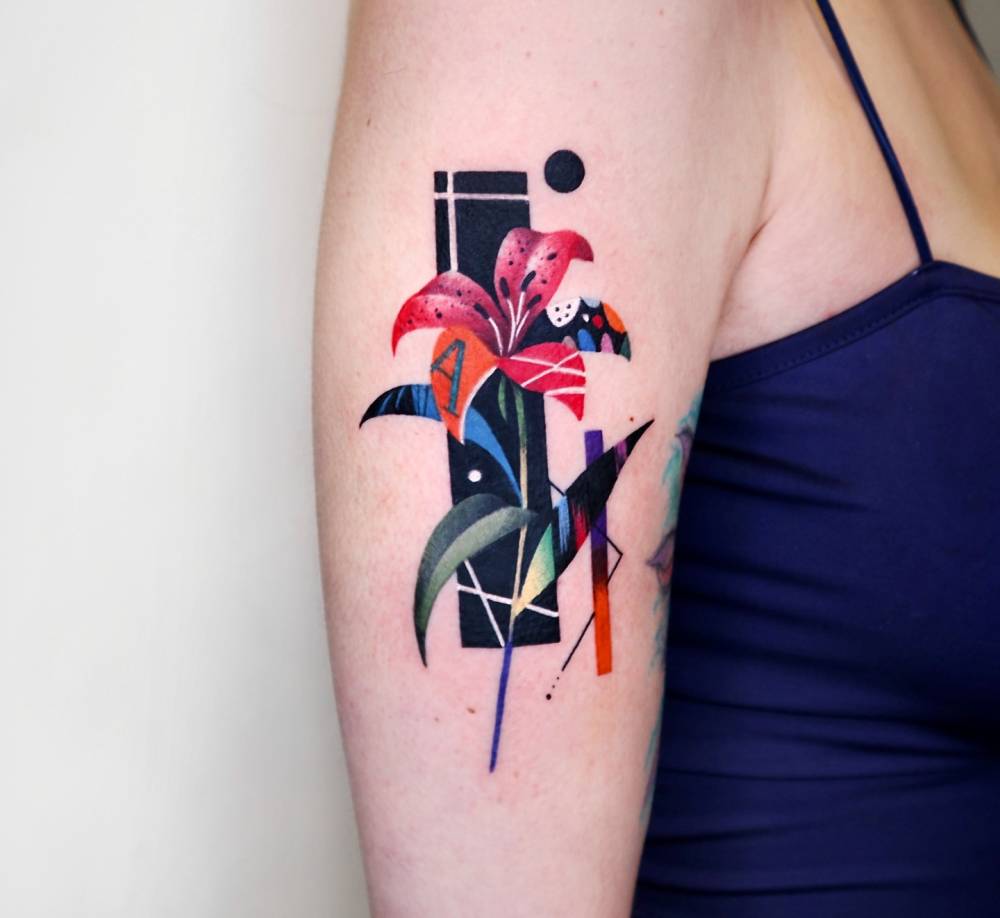 Lily flower tattoo in graphic style placed on the upper arm.