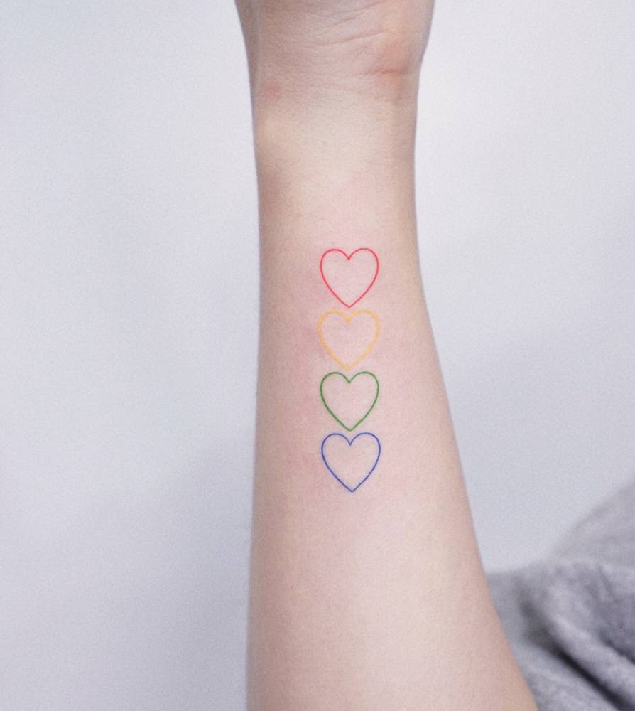 Colorful minimalistic hearts tattooed on the wrist.