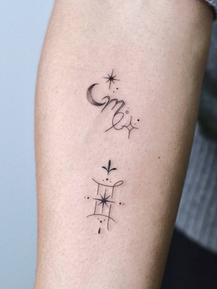 Scorpio and Gemini zodiac symbols tattooed on the inner forearm.