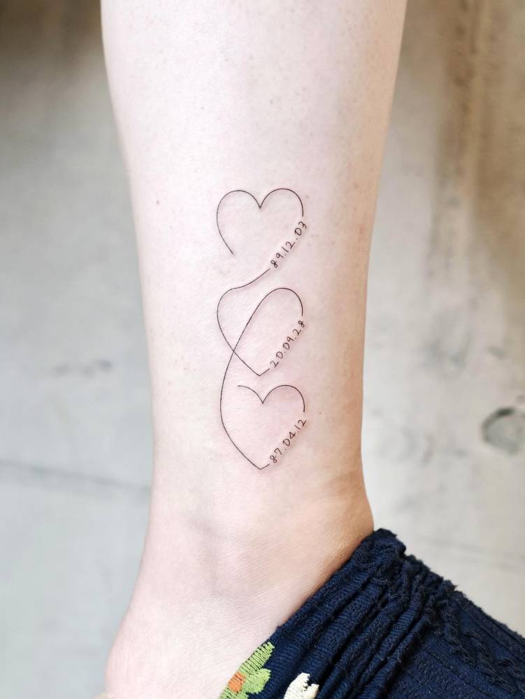 Hearts and dates tattoo located on the ankle, fine line style.