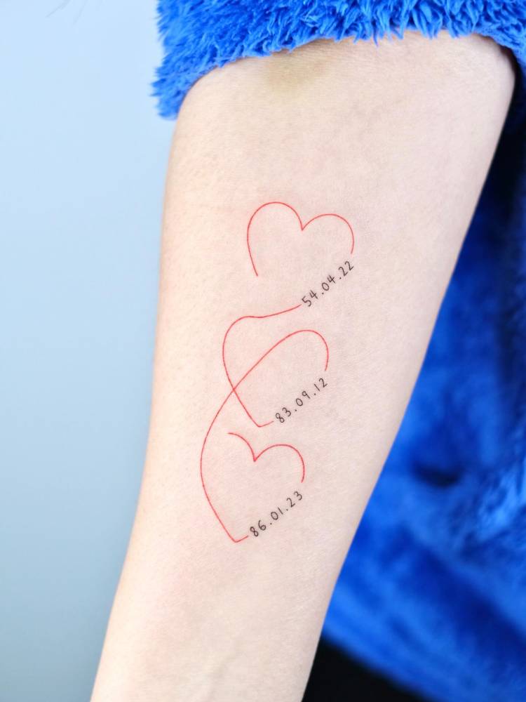 Red hearts and dates tattoo located on the inner forearm, fine line style.