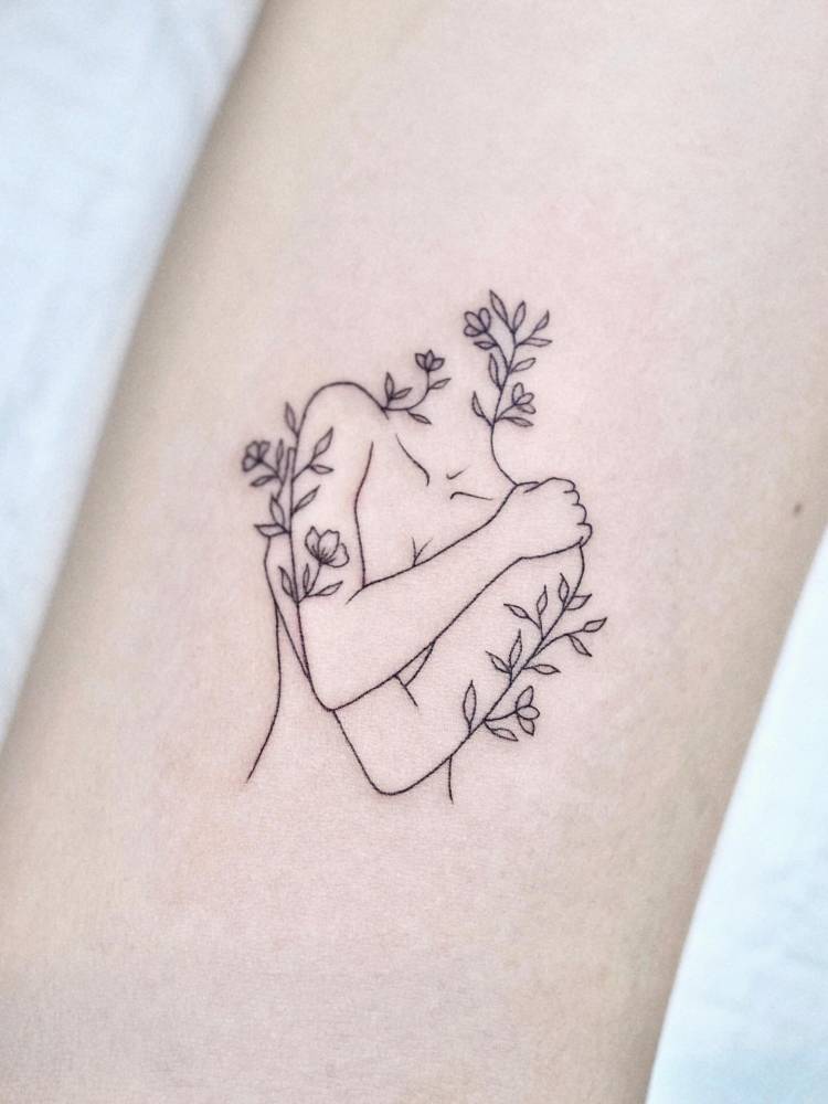 Self hug tattoo located on the bicep, done in fine line style.