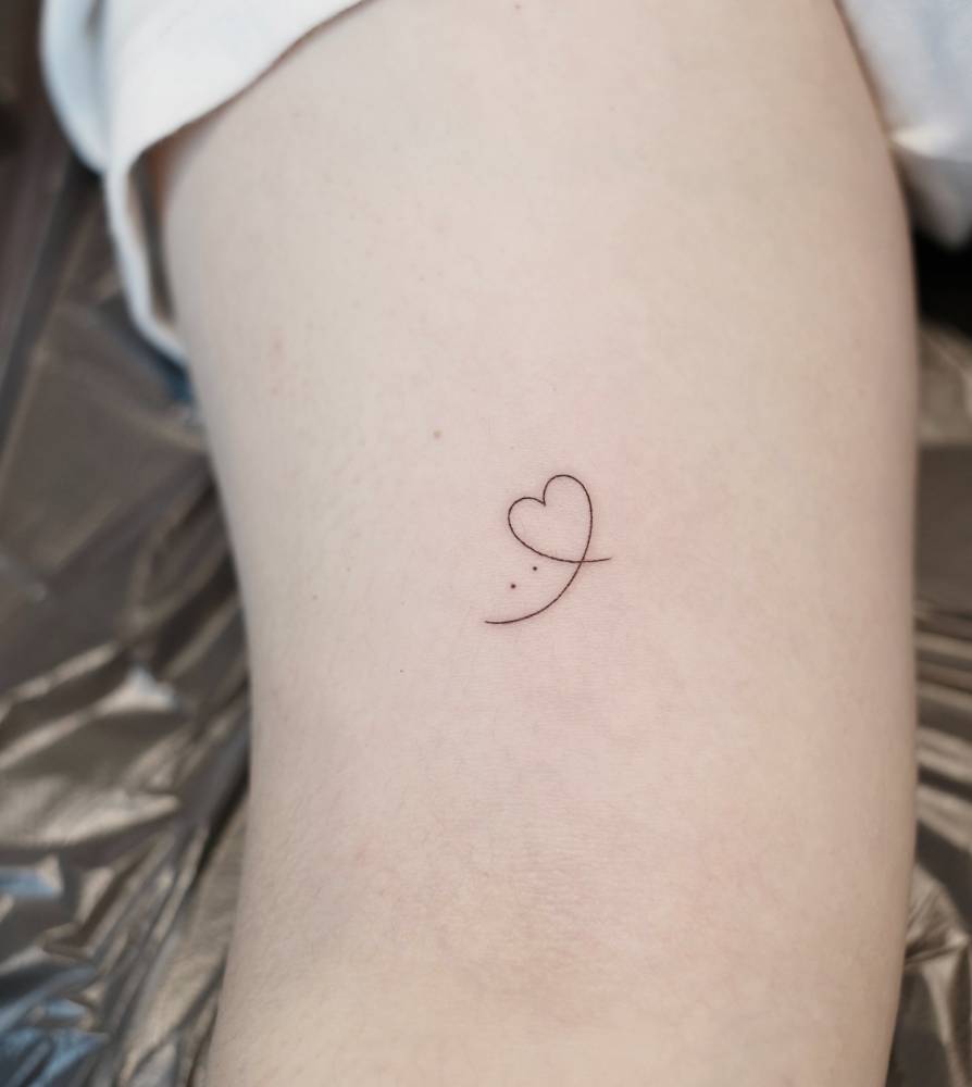 Smiley face and heart tattoo located on the bicep, minimalistic style.