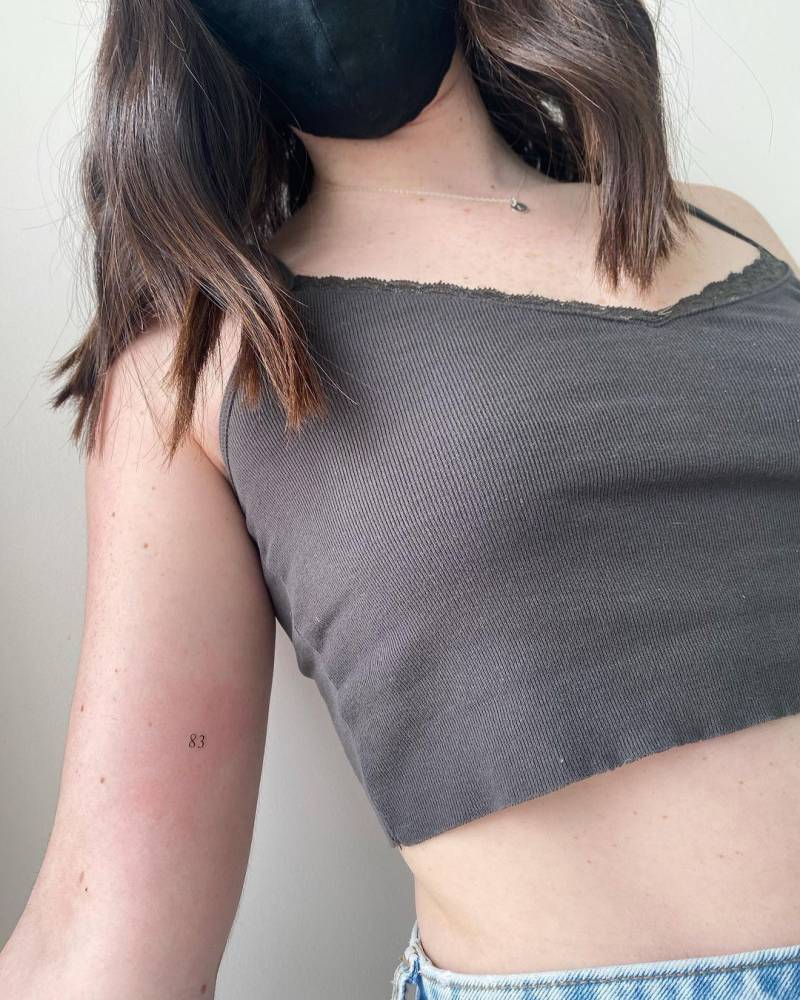 Number "83" tattooed on the inner forearm