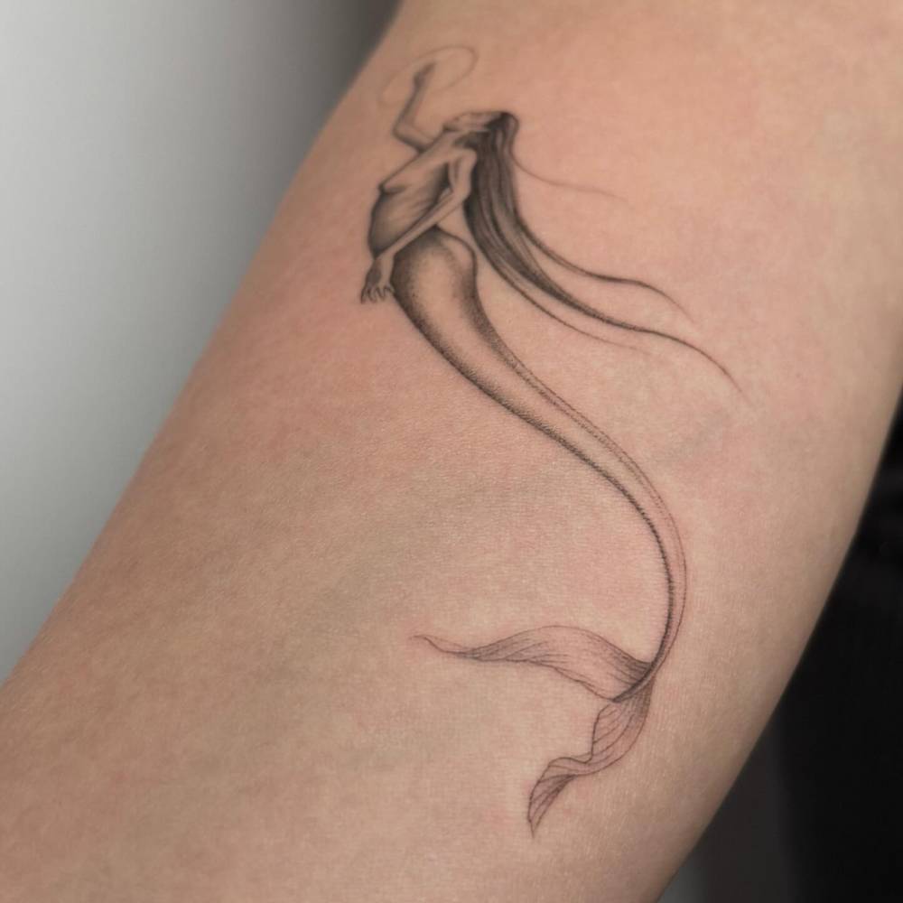 Single needle mermaid tattoo located on the inner forearm.