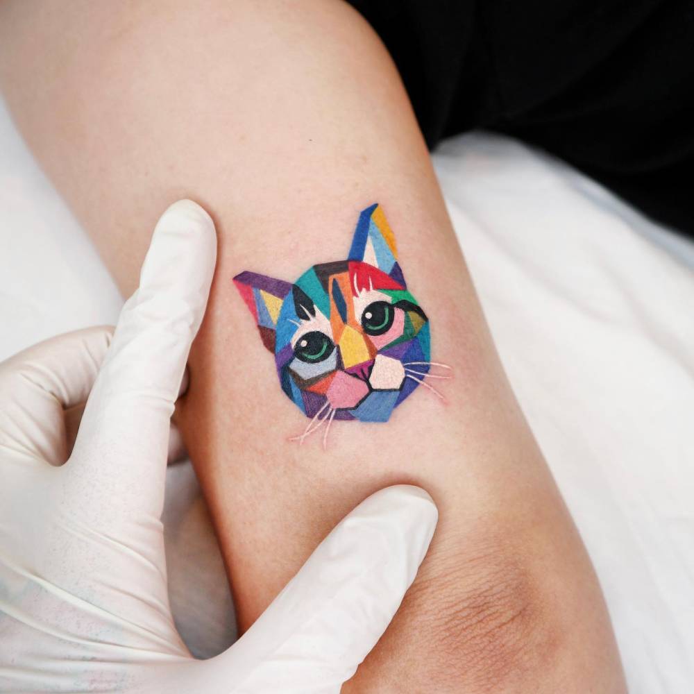 Geometric style cat portrait tattoo located on the tricep.