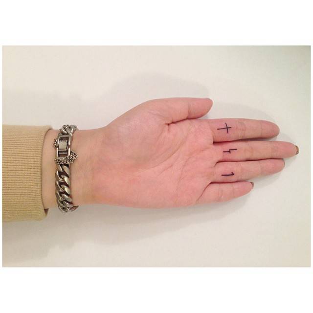 Cross and numbers "4" and "1" tattoos located on the fingers.
