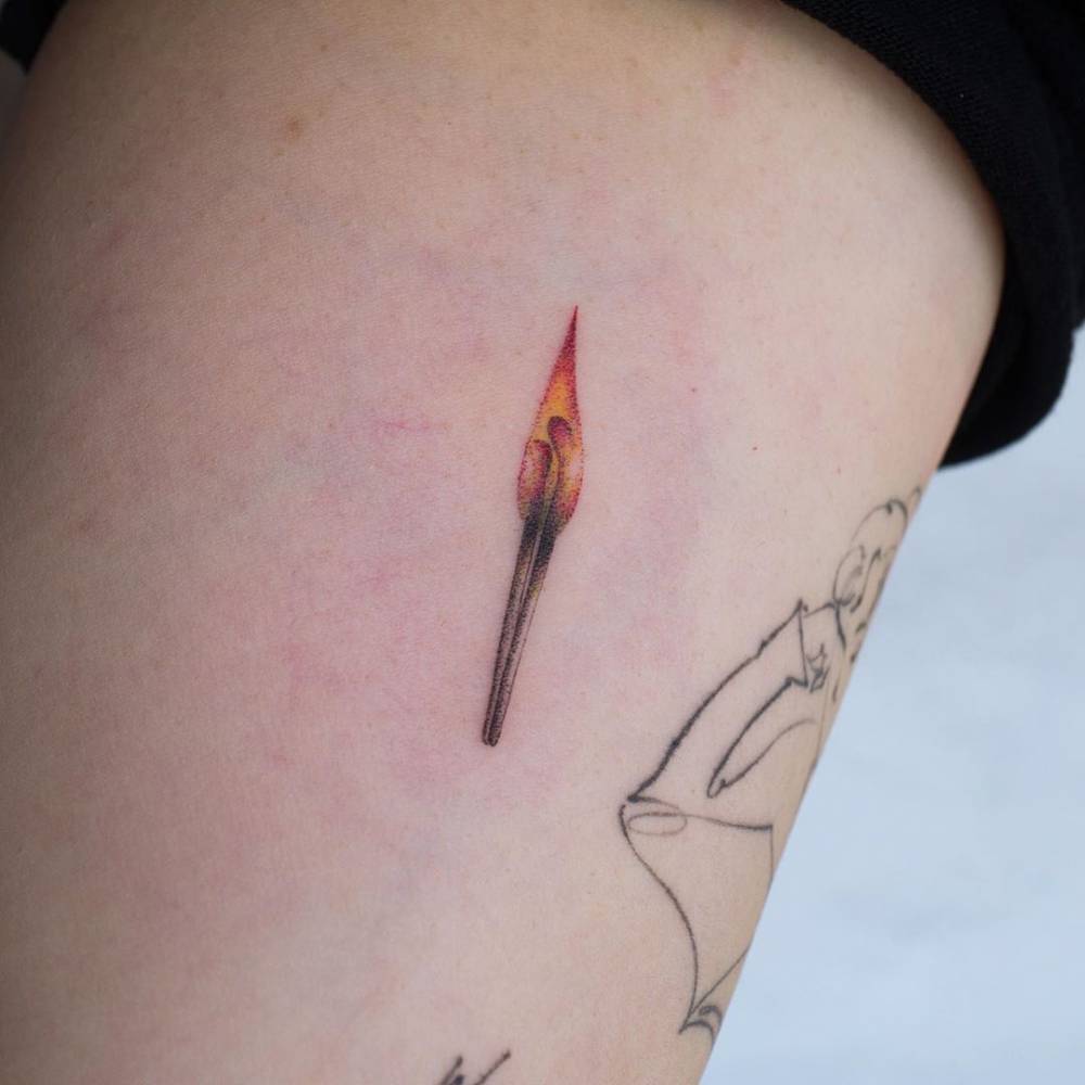 Matchstick tattoo in illustrative style placed on the inner arm.