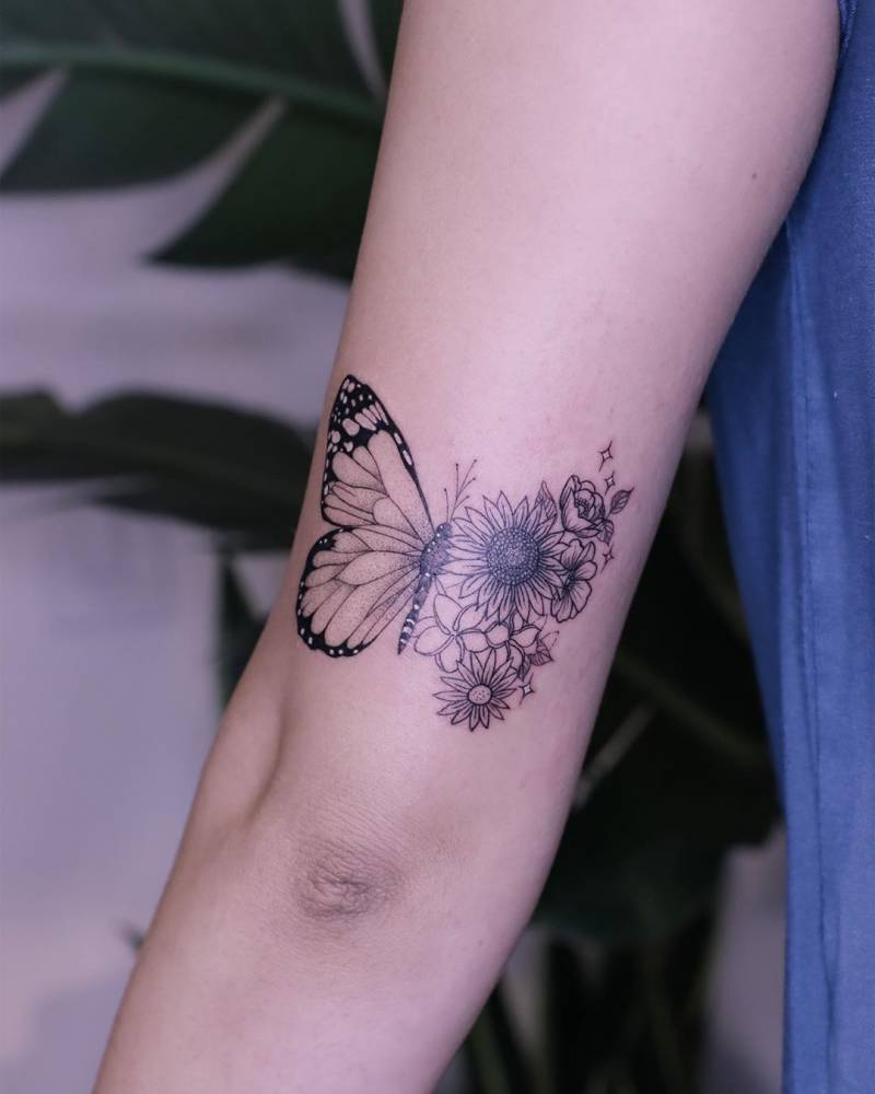 Half butterfly half flowers tattoo located on the tricep.