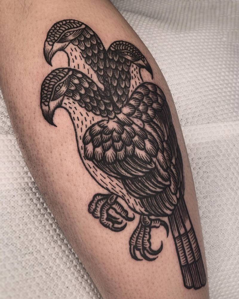 Engraving style three headed hawk tattoo located on the calf.