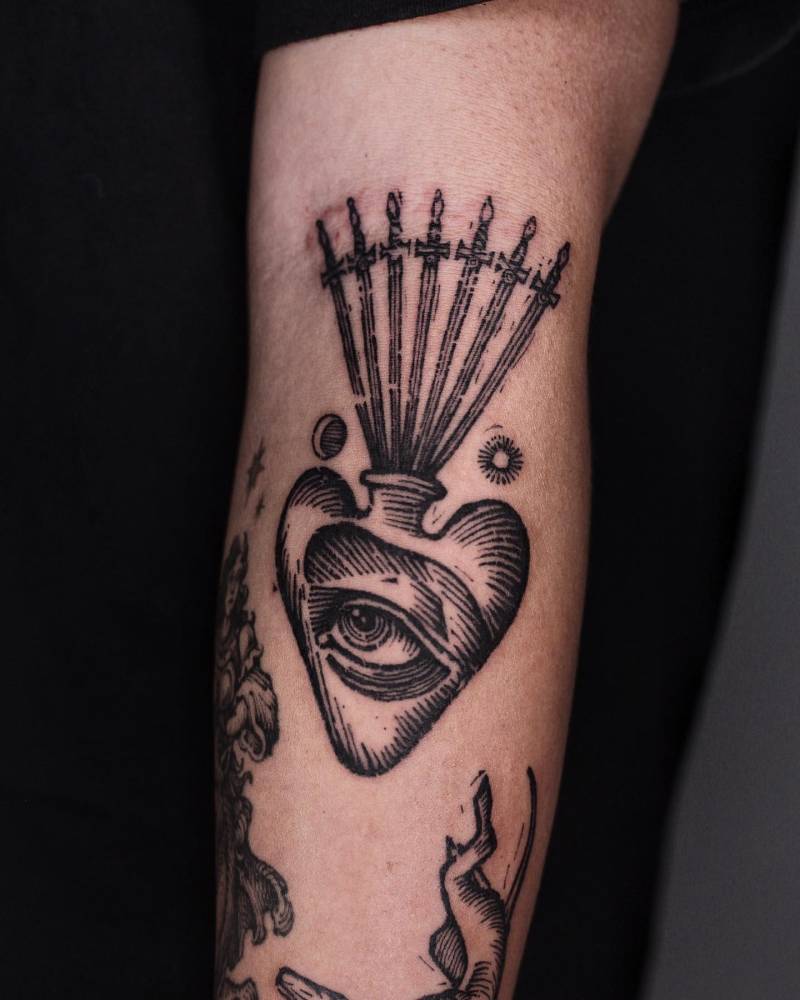 Eye heart and swords tattoo in engraving style located on the inner forearm.