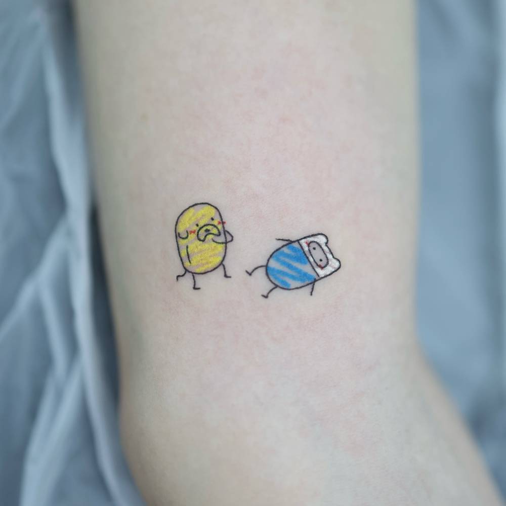 Jake and Finn tattoo located on the inner arm, cartoon style.