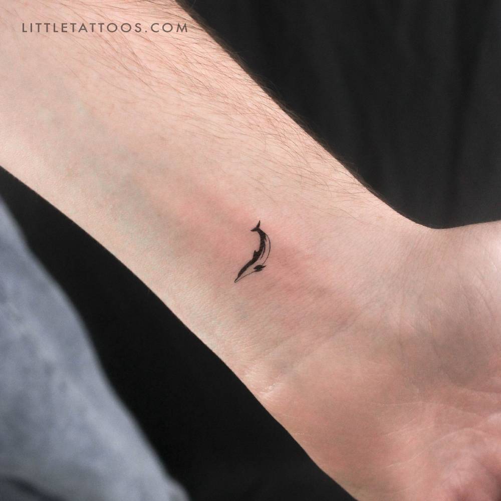 Tiny dolphin temporary tattoo located on the wrist.