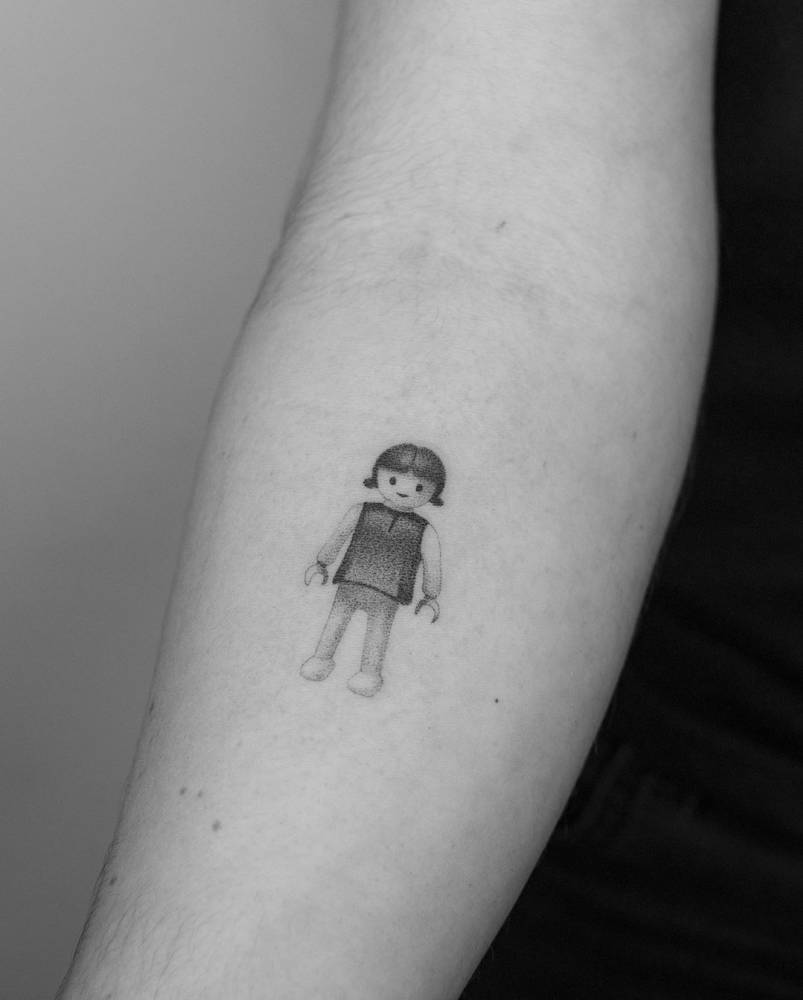 Hand poked Playmobil tattoo located on the inner forearm.