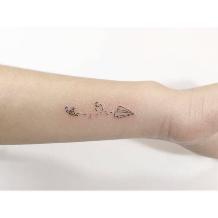 Minimalistic universe and paper plane tattoo located on the wrist.